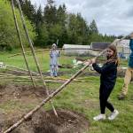 Photo by Cary Peterson
Sixth grader Ellie Aernie and AmeriCorps Service Member Lily Cowan, right, put a bamboo pole into place for the teepee-like structure scarlet runner beans will grow on.