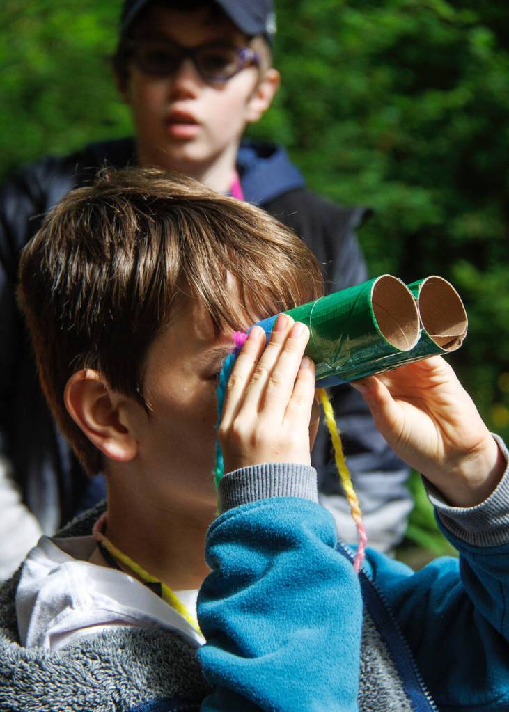 Fourth grader Cam Pelletier, front, uses a pair of binoculars  made out of toilet paper rolls and duct tape  to look for birds. His classmate Jude Johnson, back, looks on. (Photo by David Welton)