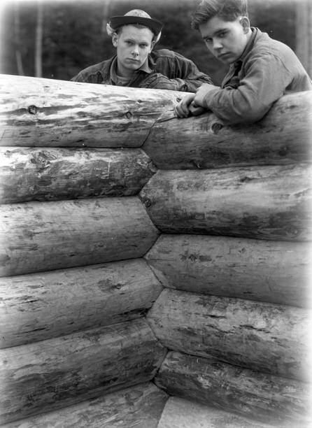 Washington State Archives photo
Two crew members stand behind the walls of a log house under construction in the 1930s.