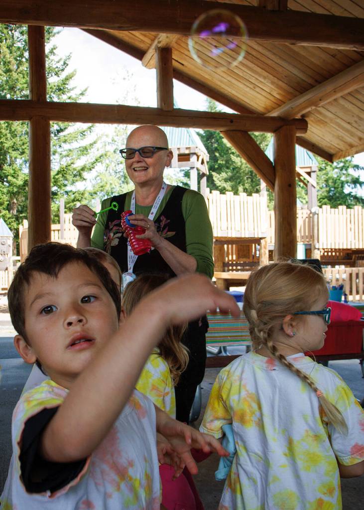 Library employee Tracy Miller blows bubbles for children at Family Story Time at Castle Park on Wednesday. (Photo by David Welton)