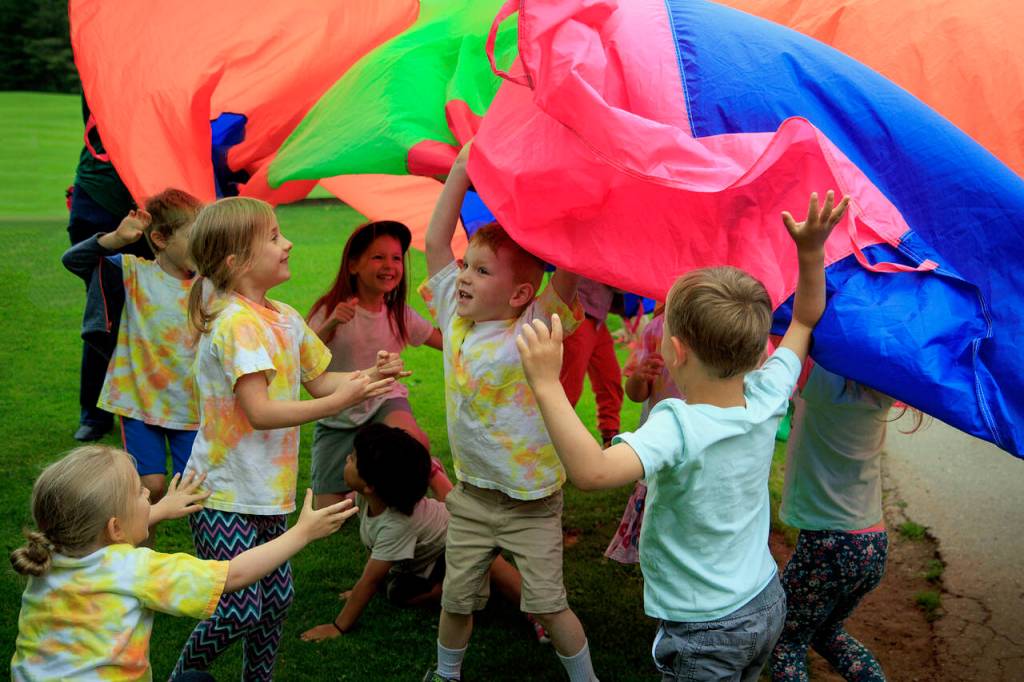 Kids play under a parachute at Family Story Time at Castle Park in Langley July 6. (Photo by David Welton)