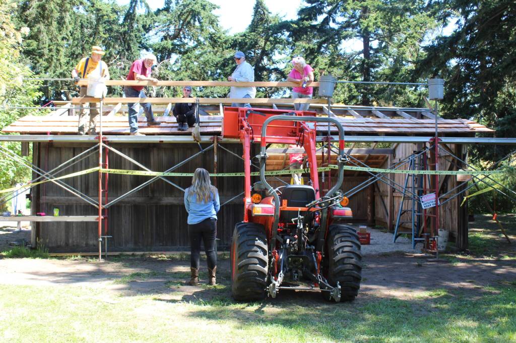 Volunteers from Michigan and other states work on roof construction and other repairs at the Pratt Machine Shed July 20. (Photo by Karina Andrew/Whidbey News-Times)