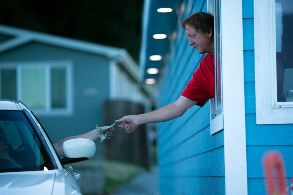People pay at the window for movie tickets at the Blue Fox Drive-In Theater. (Ryan Berry / The Herald)