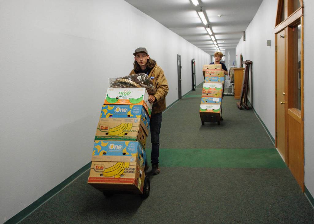 Lars Hetland, left, and Maxwell Whitingham clear out the back room of Good Cheer Two. (Photo by David Welton)