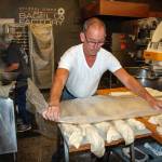 John Auburn cuts and shapes bagels. In the back, Carol Forgas boils them. (Photo by David Welton)