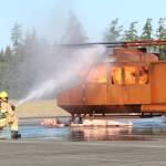 Photo by Karina Andrew/Whidbey News-Times
A Navy firefighter aims a hose at a helicopter fire during an emergency simulation at Outlying Field Coupeville Aug. 17.