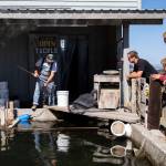 Customers wait as Dan Cooper fishes live herring out of his holding pond. (Olivia Vanni / The Herald)