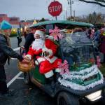 Photo by David Welton
Riding in a golf cart, Santa receives some assistance from merchant Fred Lundahl, who owns Music for the Eyes.