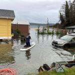 A Central Whidbey Island Fire and Rescue firefighter paddleboards between flooded homes in Greenbank. (Photo provided)