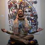 Photo by David Welton
Dressed in brightly tie-dyed clothing he made himself, Ian Joseph Jackson strikes a meditative pose in front of his artwork that includes Martin Luther King Jr. at the podium.