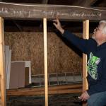 Holmes Harbor Activity Club President Andy Campbell points out the chalked phrase beneath Freeland Hall, Arnold Hugley loves Betty Jean Blankenburg. The buildings crawl space has many other affirmations of love written throughout it, which likely date back to the 1940s. (Photo by David Welton)
