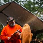 Flakes of wood and sawdust spray in different directions while Steve Backus works on the details of a moon carving. (Olivia Vanni / The Herald)