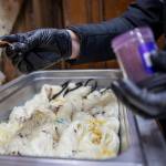 Willow Mietus, 50, sprinkles powered dye on white yarn. (Annie Barker / The Herald)