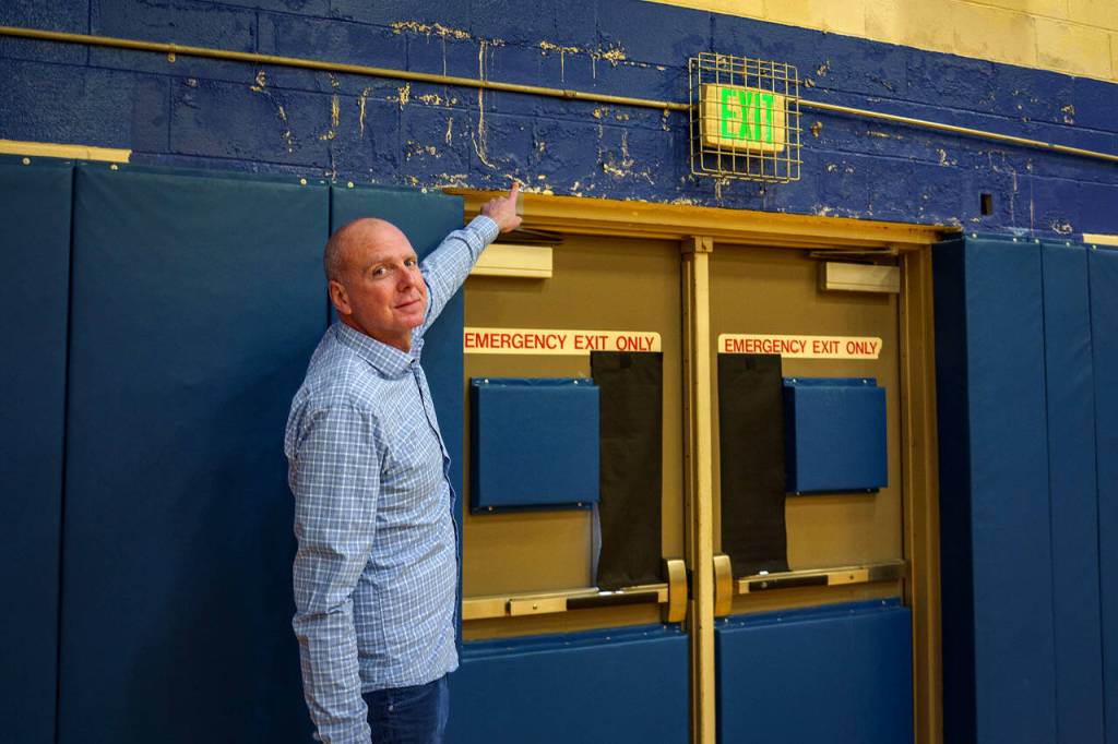 South Whidbey High School Principal John Patton points out water damage on the cinder block walls of the gym. (Photo by David Welton)