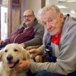 From left, Phill Neff and Gerald Henrich meet therapy dog Falkor.