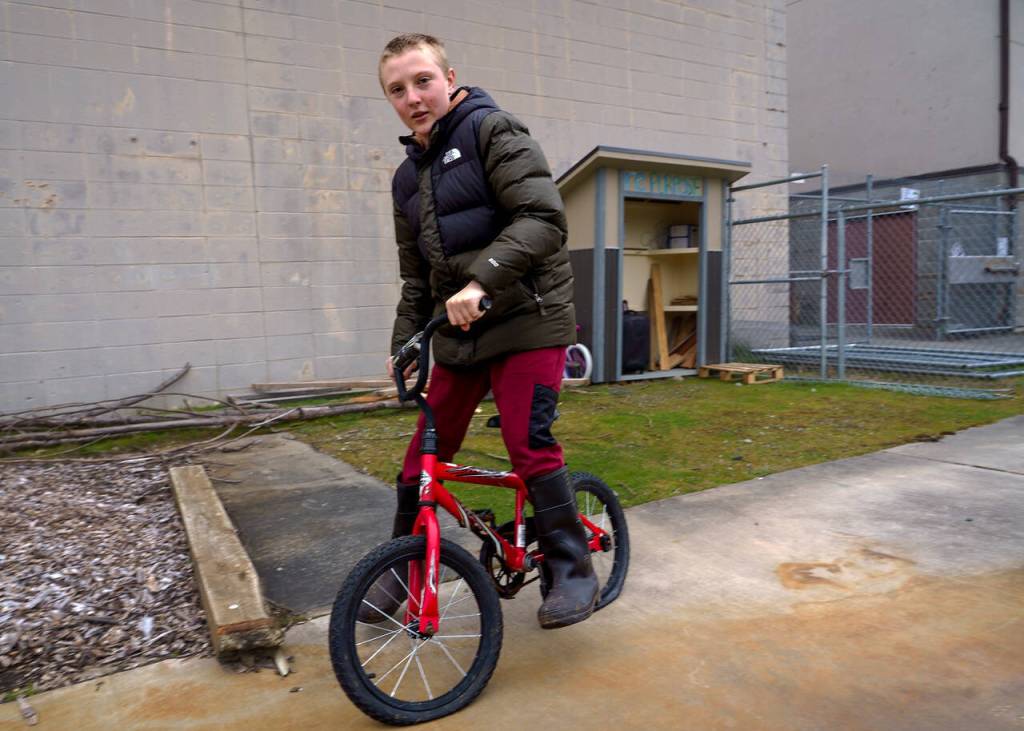 Will Conners rides away on a bicycle he plans to turn into a three-wheeler. The bike is one of the items at rePurposes reuse kiosk. (Photo by David Welton)