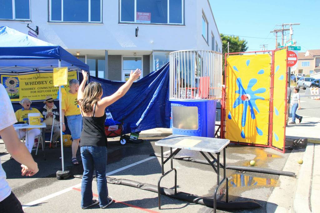 Chelsea Kawi celebrates as she successfully hits the target, causing Rep. Dave Paul to fall into the tank. (Photo by Luisa Loi)