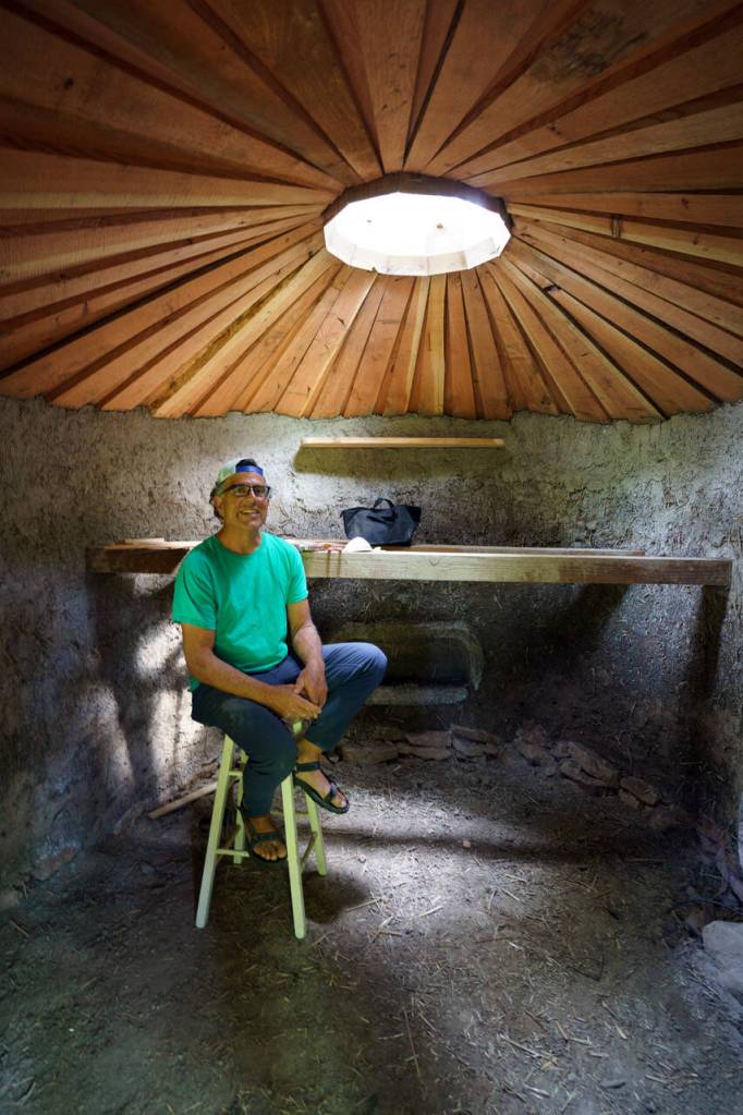 Eli Adadow sits inside one of his newer yurts, which will have a loft bed. (Photo by David Welton)