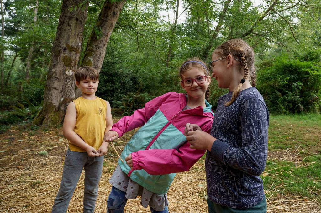 Photo by David Welton
From left, cousins Gus Black, 7, from Seattle, Katie Olin, 7, from Lynnwood and Sally Gibbs, 8, from Edmonds play in the woods at Full Moon Rising Farm.