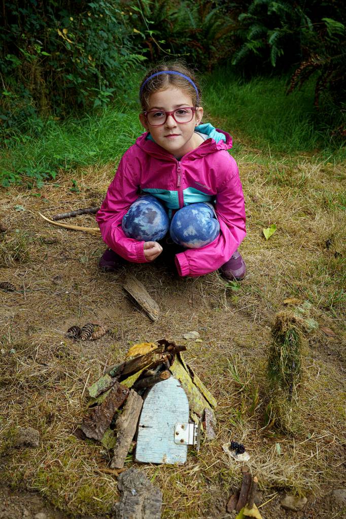 Photo by David Welton
Katie Olin, 7, of Lynnwood crouches beside the fairy house she built during Green Arts Camp.