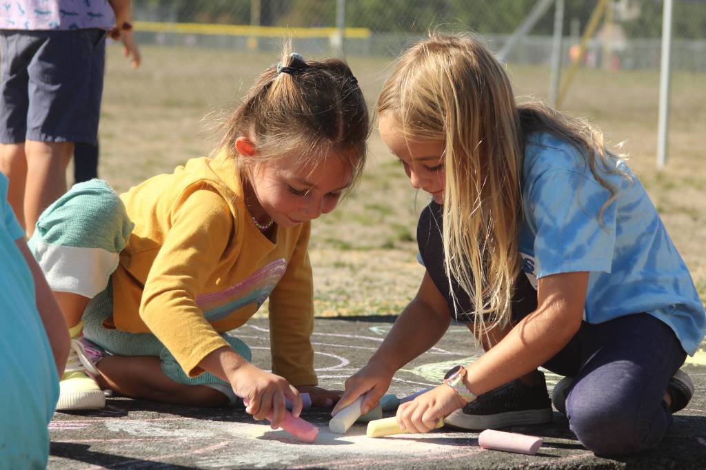 Photo by Karina Andrew/Whidbey News-Times
First graders Isla Stewart, left, and Millie Kindred help chalk the walk Sept. 15 at Hillcrest Elementary School.