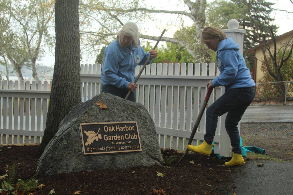 Oak Harbor Garden Club members Kathy Chalfant, left, and Helene Valdez tend to a plot in Smith Park, where the club has been presented with a plaque in honor of its contributions to the city. (Photo by Karina Andrew/Whidbey News-Times)