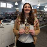 Langley Library Manager Kaley Costello with stickers commemorating the librarys 100th birthday. (Photo by David Welton)