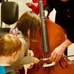 Kids try playing a double bass during a past instrument petting zoo. (Photo provided)
