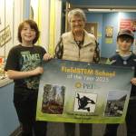 From left, David Bryant, 11, South Whidbey Elementary School Principal Susie Richards and Carter Poolman, 10, hold up a banner celebrating the FieldStem School of the Year award. (Photo by Kira Erickson/South Whidbey Record)