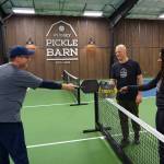 From left, Timm Sanford, Paul and Abi Tschetter tap paddles, a customary gesture after a game of pickleball. (Photo by David Welton)