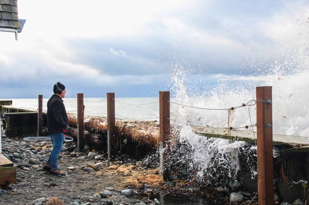 Marie Francos husband, Lenny, avoids the splash while taking a short break from cutting a log brought by Tuesdays storm. (Photo by Luisa Loi)