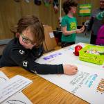 Second grader Coniah Pitts adds information to a poster about pollinator habitats. Students part of South Whidbey School Districts ALE program are set to present climate science projects next week in Olympia. (Photo by David Welton)