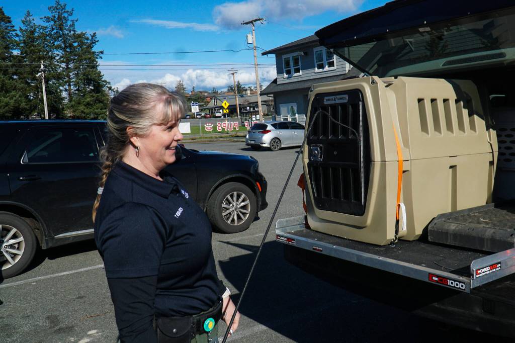 Whidbey Island animal control officer Tammy Esparza displays a kennel from the back of the animal control pick-up. (Photo by Sam Fletcher)