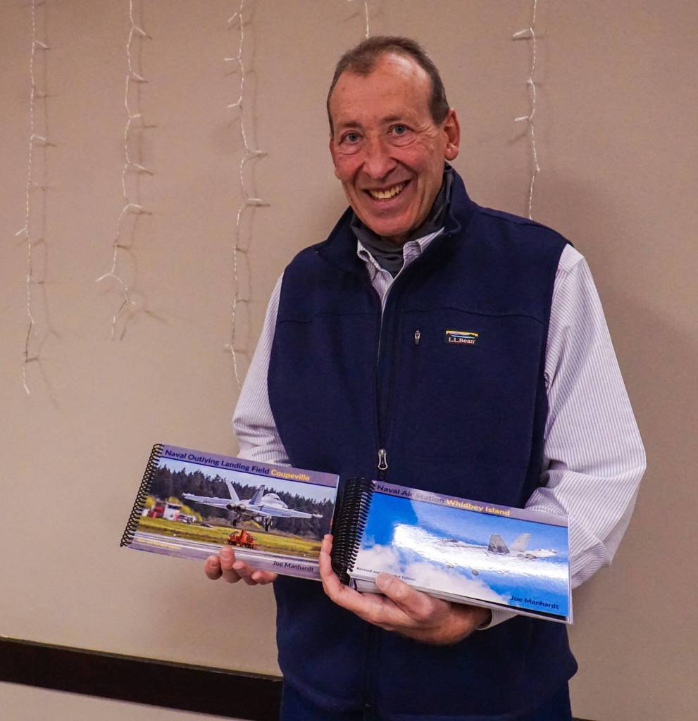 Photographer Joe Manhardt holds at his books, Naval Air Station Whidbey Island and Naval Outlying Landing Field Coupeville. (Photo by Sam Fletcher)