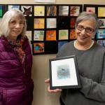 Artist Cyndy Jensen, right, holds up a framed art piece made by Karen Rothboeck, left. (Photo by David Welton)