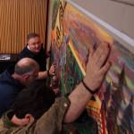 Mayor Ronnie Wright (left), faculties worker Tom Wade (middle) and artist Nick Mann (right) install Song of the Salish Sea in council chambers. (Photo by Sam Fletcher)