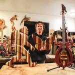 Chad Pilkington, a wood carver who lives in Oak Harbor, poses in his garage with some of his creations: Bigfoot, a butterfly and a hieroglyph guitar. (Photo by Luisa Loi)