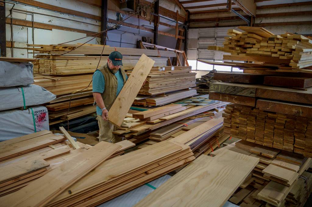 Bret Christensen sorts through a pile of wood in Whidbey Millhouse, the business he co-owns in Freeland with his son, Maverick. (Photo by David Welton)