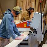 Gus Gordon, left, feeds a plank of wood through a machine. (Photo by David Welton)