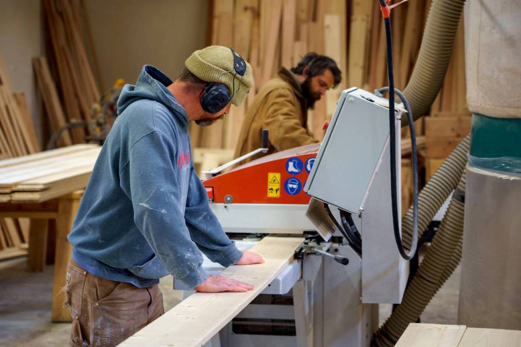 Gus Gordon, left, feeds a plank of wood through a machine. (Photo by David Welton)