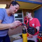 Art teacher Denice Bochantin helps second grader Coniah Pitts heat the colorful strips of a water bottle. (Photo by David Welton)