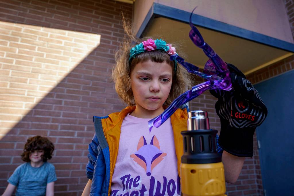 Third grader Irene Doleshel watches her painted water bottle transform with the help of a heat gun. (Photo by David Welton)