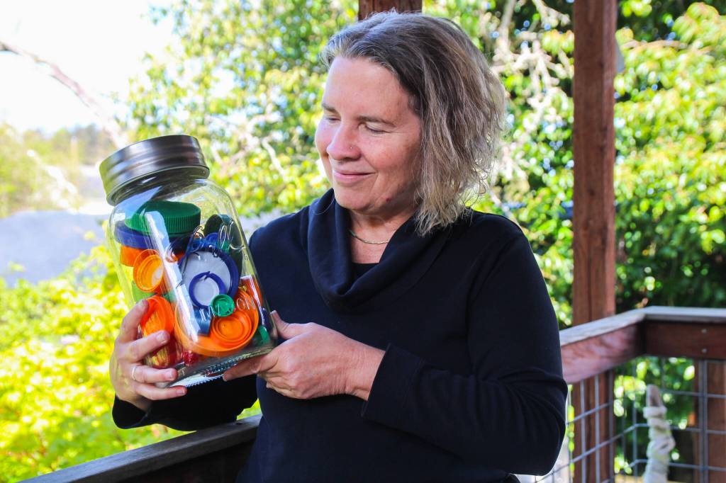 Zero-waste Artist Joan Green holds a jar of colorful lids she might use for an art piece. (Photo by Luisa Loi)