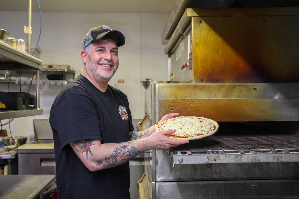 Photo by Luisa Loi
Jason Youngsman, owner of Lava Louies, is about to place a reporters pizza in a conveyor oven. Youngsmans pizza follows his fathers pizza recipe that is over 30 years old.