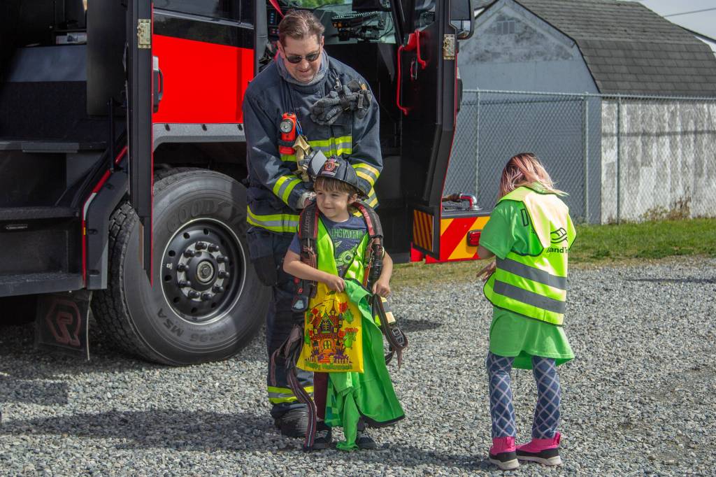 Photo by Caitlyn Anderson
Siblings Lukas and Raelynn Walker stand next to a firetruck while Lukas tries on an oxygen tank at the Touch-a-Truck event.