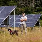 (Photo by David Welton)
Britt Fletcher and Shep the farm dog stand before an array of solar panels. Earlier this year, Mutiny Bay Blues was awarded a $78,800 grant from USDA to purchase and install them.