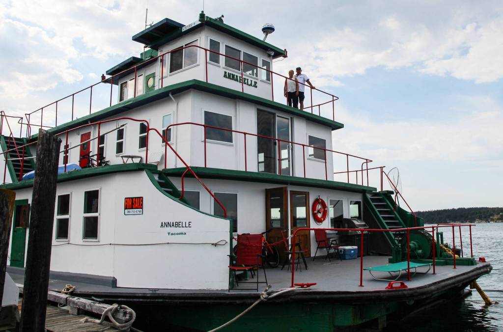 Kat and Dennis Redmon smile from the top floor of their 34-foot-tall ferry home while docked at the Coupeville Wharf. (Photo by Luisa Loi)