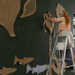 Local artist Melissa Koch tapes up paper cutouts to visualize where her art work will go in downtown Langley. (Photo by Caitlyn Anderson)