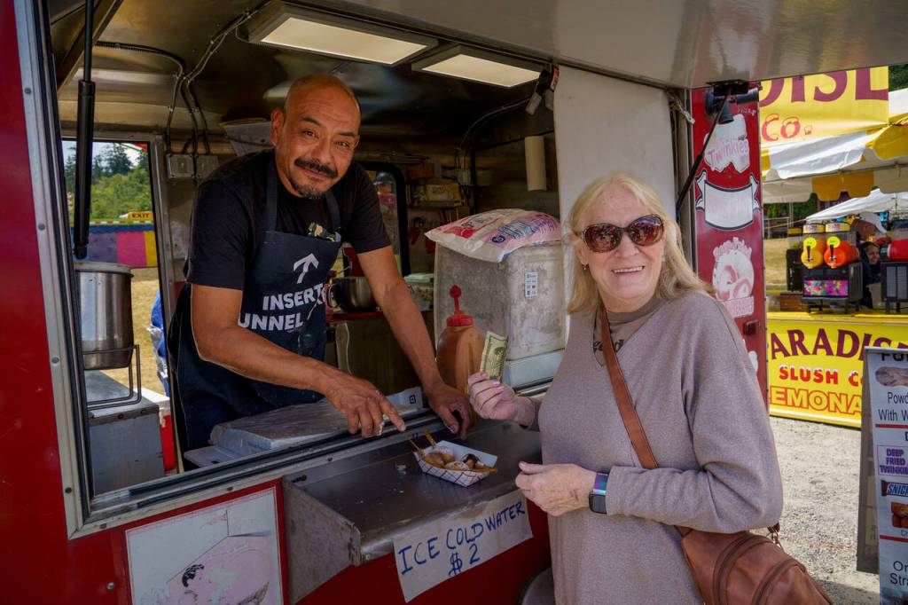 Fried foods vendor Roberto Martinez hands Jo Ellen Margenau of Wisconsin her very first chunk of deep-fried butter. (Photo by David Welton)