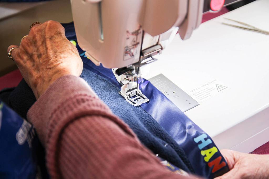 Mary Fyfe sews a ribbon to a blanket. (Photo by Luisa Loi)